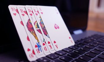 playing cards on top of a laptop's keyboard while leaning on the laptop's screen monitor